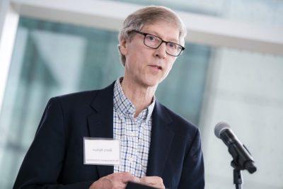 Researcher in navy jacket stands at microphone